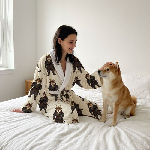 Woman wearing a robe with bear designs sitting on a bed with a dog.