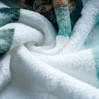 Close-up of textured white fabric with blue and brown accents. Folded robe material with a pattern of cats on a white background. The material is flannel. 